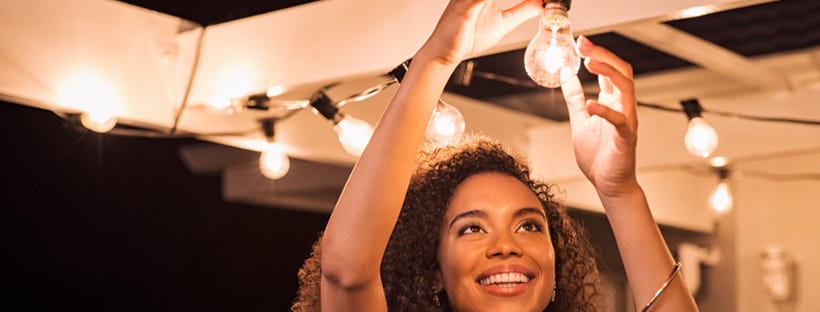 Young woman putting up light bulbs