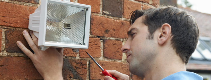 Man fixing security light on a wall